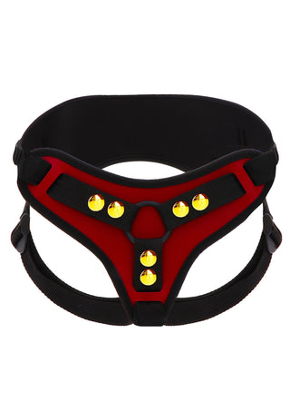 Röd och svart strap-on-sele med gula nitar, justerbara remmar och en O-ring framtill.