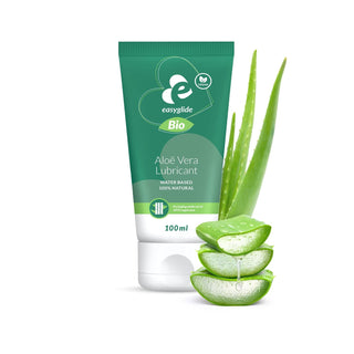 Aloe Vera Bio Glidmedel 100ml i grön tub, med aloe vera-växt och skivor mot vit bakgrund, framhäver dess naturliga ingredienser.