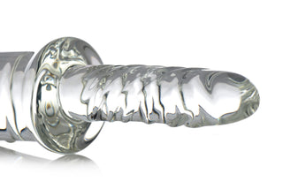 En genomskinlig, räfflad dildo av borosilikatglas med en utvidgad bas, avbildad mot en vit bakgrund.