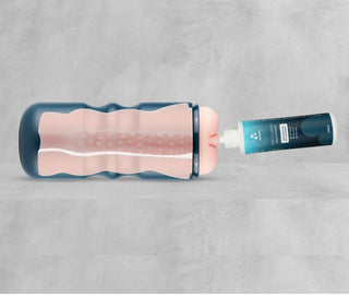 En blå flaska med silikoninredning fylls med EasyGlide Masturbator Gel 250ml, en extra smidig, vattenbaserad formula, från en tub på en ljusgrå bakgrund.