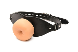 Ass Face Mun-Gag Beige har en svart läderrem och en silikonplugg formad som en mun, perfekt som BDSM leksak eller mun-gag. Visas mot en vit bakgrund.