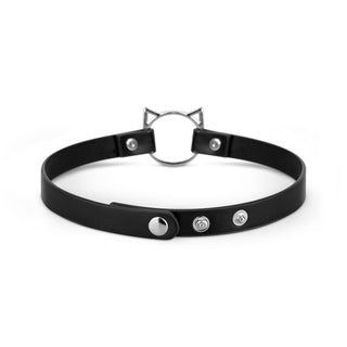 Svart choker i läderimitation med metallnitar, en central ring och kattörondetaljer; justerbar spänneförslutning.