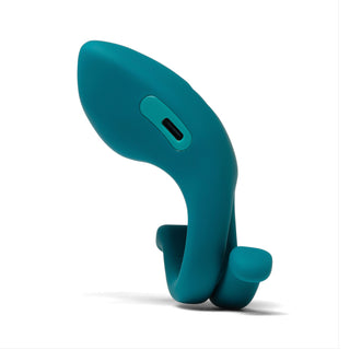 Dame Hug Adjustable Cock Ring, tillverkad av kroppssäker silikon med en laddningsport, visas i blågrönt på en vit bakgrund.