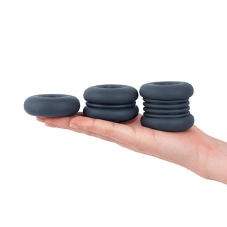 Tre penisringar av svart silikon i olika storlekar, staplade på varandra, visar flexibel design.