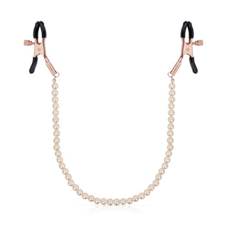 Bröstvårtsklämmor i roséguld med svarta gummispetsar och anslutande kedja i roséguld, visas mot en vit bakgrund.