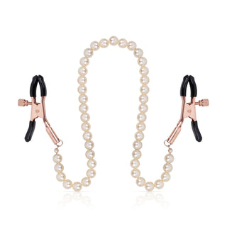 Bröstvårtsklämmor i roséguld sammankopplade med en pärlkedja, visas mot en vit bakgrund.