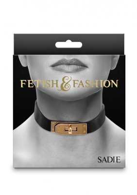 Produktlådan i gråskala innehåller Fetish & Fashions Sadie Halsband, en svart choker med guldlås. "Fetisch & mode" lyser i guld ovanför, med "Sadie" elegant placerad längst ner till höger, perfekt för dig som söker fetisch-äventyr.