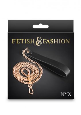 Fetish & Fashions Nyx Koppel har en enastående gyllene kedja och svart handtag, mot en mörk bakgrund.