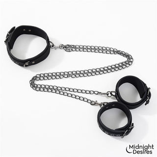 Svart halsband med fotbojor av veganskt läder och metallkedjor, avbildat mot vit bakgrund.