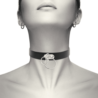 En person bär den eleganta Chocker Med 2 Ringar, gjord av svart veganskt PU läder med silverringar. Ansiktet är delvis synligt från näsan och nedåt. Chokern har en justerbart-design för en perfekt passform.
