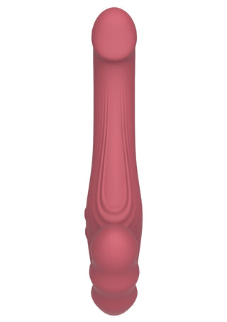 Rosa strap-on-vibrator i silikon utan remmar, med rundade, strukturerade ändar, fotograferad uppifrån mot en vit bakgrund.