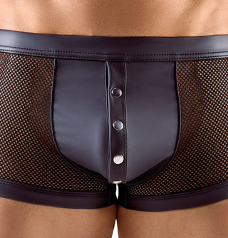 En närbild visar en person som bär Herrboxer i Svart Mesh, med svarta mesh-boxertrosor med en solid frontpanel och tre metallknappar. Nätsidorna avslöjar delvis huden, vilket ger ett stilren utseende när personen står mot en vanlig bakgrund.