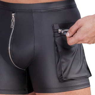 Närbild på en person som bär NEK Pants Matt Svart - åtsittande svarta skinnbyxor med blixtlåsförsedd cargo-ficka - när han öppnar fickans blixtlås.