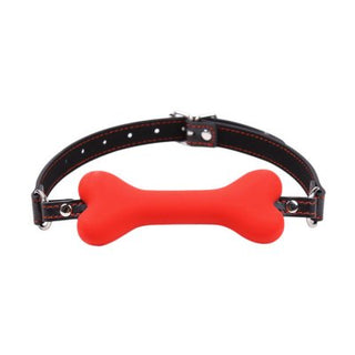 Röd Bone Gagball är en röd benformad gag i silikon med en justerbar svart rem, med metallöglor och ett spänne, perfekt för att förbättra din bondage-upplevelse.