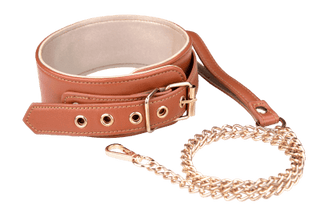 Halsband med Kedja Cognac har ett rikt brunt läder med ett metallspänne och öljetter, tillsammans med ett guldfärgat kedjekoppel och matchande läderhandtag, isolerat på en vit bakgrund för klarhet.