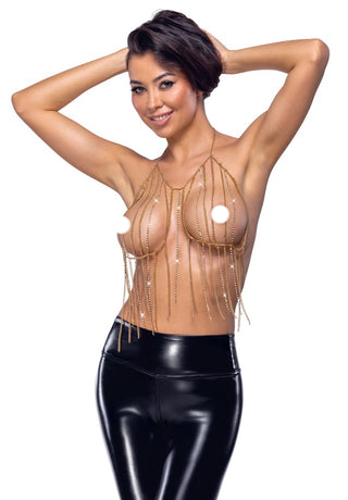 Leende kvinna poserar i svarta latexbyxor och en Guldig Kedjetopp Med Strass, armarna lyfta bakom huvudet.