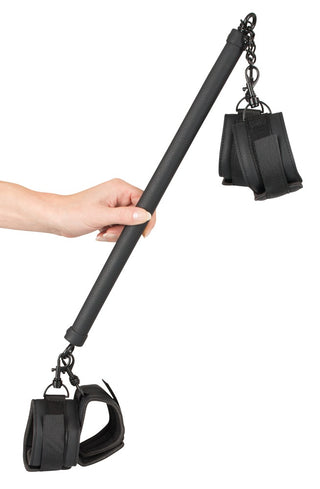 Justerbar spridarstång av metall med svarta handledsfästen, sammankopplade med silverfärgade clips och kedjor i vardera änden.