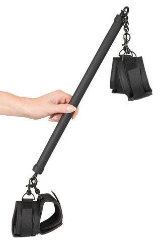 Justerbar spridarstång av metall med svarta handledsfästen, sammankopplade med silverfärgade clips och kedjor i vardera änden.