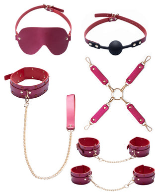 Luxury Pearl Bondage Kit i rosa konstläder innehåller ögonbindel, munkavle, halsband, handbojor, manschetter och en sele med guldkedjor.