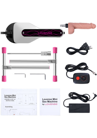 På bilden visas ett kompakt, svart Lovense Mini Sexmaskin-set med metallram, silikoninsatser, fjärrkontroll och nätadapter.