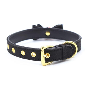 Halsband Med Rosett är en svart läderkrage med guldknoppar och spännen, vilket skapar en förförisk atmosfär med sin eleganta sidobåge.