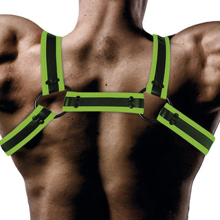 En muskulös rygg bär Shining Line Glow Bondage Harness i neongrönt och svart, tillverkad av veganskt läder med metallringar och knappar.