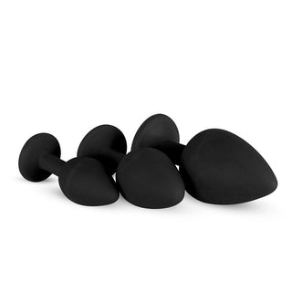 Tre analpluggar i svart silikon med utsvängda baser, arrangerade för optimal analstimulering.