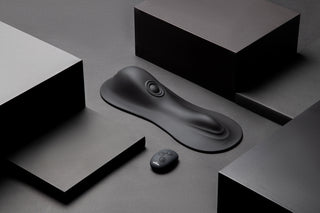 Cowgirl Rodeo Rumbler Ride-On är en elegant svart ergonomisk enhet med en liten rund fjärrkontroll, utformad för handsfree-upplevelser och accentuerad av geometriska svarta former.