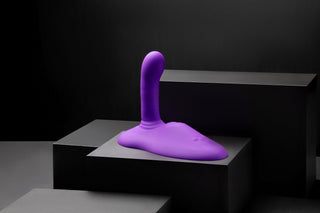 Cowgirl Rodeo Rider Thrusting, en lila kroppssäker silikon sexleksak, visas på svarta geometriska plattformar med en mörk bakgrund.