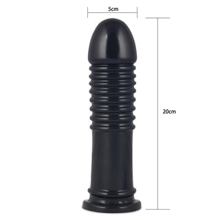 Svart, ribbad analplugg i kroppssäker PVC, 20 cm lång och 5 cm bred, avbildad stående på en plan yta.