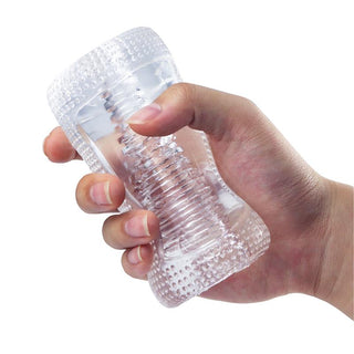 En hand håller en genomskinlig, strukturerad plastbehållare med ett spiralmönster på insidan, som påminner om det experthantverk som finns i Hannx2 Handjob Stroker.