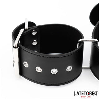 En närbild av Latetobed Neck & Wrist Cuff i svart läder med metallspänne och öljetter - ett elegant tillskott till din BDSM-samling.