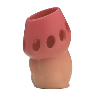 Elastisk TPR-penishylsa med persikofärgad bas, rosa spets, cirkulära öppningar längs skaftet och en vinklad ingång.