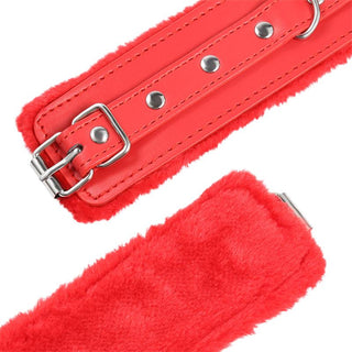 Närbild av Latetobed Fur Handcuffs med foder av röd fuskpäls, läderrem, metallspänne och nitar.