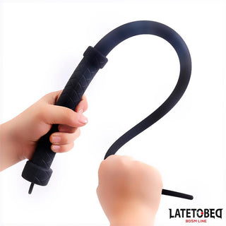 Två händer greppar Latetobed Silicone Whip 61 cm, med LATETOBEG BDSM LINE-logotypen synlig - perfekt för dominansspel och intensiva BDSM-sessioner.
