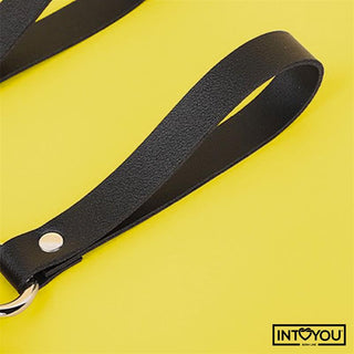 En svart veganskt läder handledsrem med en metall nit på en gul bakgrund, INTOYOU logotyp i hörnet-Bubu BDSM Teddy Nyckelring är en snygg dekorativ nyckelring för alla samlingar.