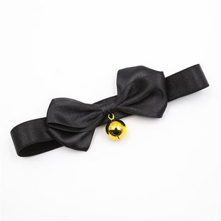 BDSM-halsbandet Black Bow har en satinsvart rosett och en guldfärgad bjällra på en vit bakgrund.