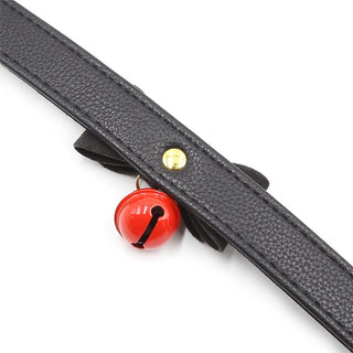 Halsband Med Rosett är ett svart läderband med en guldnit och en röd klocka, perfekt för att skapa en förförisk atmosfär i erotiska rollspelsscenarier.