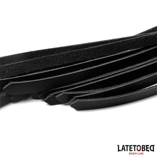 Närbild av svarta läderremmar från Latetobed Läderflogger 50 cm, idealisk för BDSM-lek, med LATETO BEG BDSM LINE-logotypen i nedre högra hörnet.