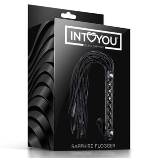 Black Sapphire Vegan Flogger har mjuka veganska strängar och ett texturerat handtag, förpackat i elegant, glansig INTO YOU-förpackning märkt "Black Sapphire Vegan Flogger.