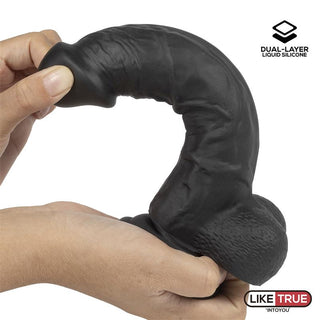 En person håller i LikeTrue Realistisk Dildo 20 cm, en svart silikonleksak med en strukturerad yta, med tvålagers silikonteknologi för att efterlikna känslan av flytande silikon.