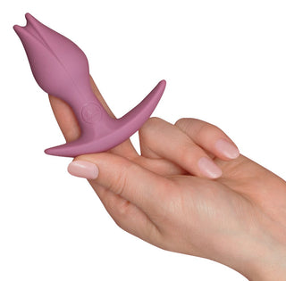 En hand håller en rosa, tulpanformad silikon Fun Factory Bootie Fem med en böjd bas mot en vanlig bakgrund, perfekt för att upptäcka nya dimensioner av anal njutning.