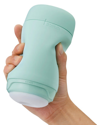 En hand håller en Tenga Puffy Masturbator Mint Grön, en ergonomisk mintgrön plastbehållare med en unik massagestruktur för komfort och en LÅST etikett nära basen.