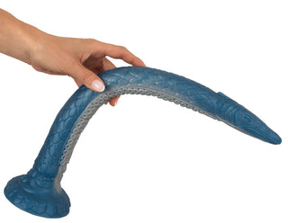 En hand böjer Ultra-Lång Tentakeldildo, en blå fantasitentakelleksak med fjäll och en sugkoppsbas, tillverkad av hygienisk flytande silikon.