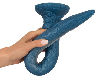 En hand håller Ultra-Lång Tentakeldildo, ett blått, ormformat dekorativt föremål med texturerade fjäll, en utsvängd bas och en unik fantasifull tentakeldesign.
