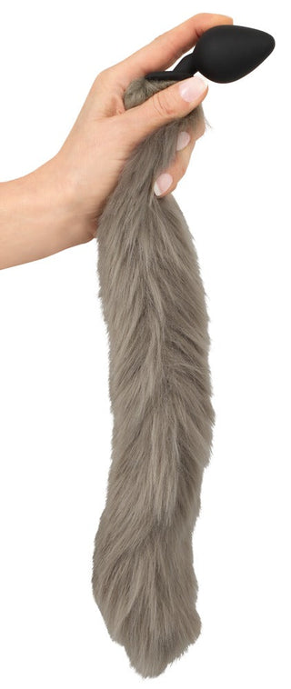 En hand håller i Fluffy Tail Buttplug, med en grå pälsstruktur och en svart pluggände, mot en vanlig vit bakgrund. Perfekt för cosplay- eller husdjursfans som är ivriga att förbättra sina fantasifulla upplevelser.