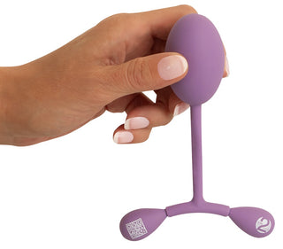 En hand håller i Vaginal Trainer Bouncing, en lila silikonapparat med två viktade ändar och en QR-kod, idealisk för effektiv bäckenbottenträning och -stärkning knipmuskler.