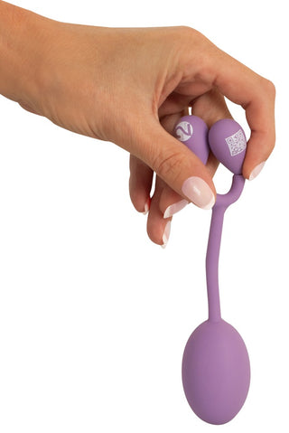 En hand håller i Vaginal Trainer Bouncing, en lila silikonapparat med en återvinningssladd och kontrollknappar - perfekt för bäckenbottenträning och för att stärka dina knipmuskler.