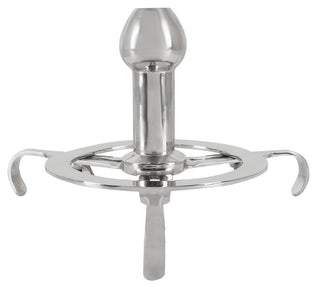 Anal Spreader Deluxe Stål är ett stativ i rostfritt stål med tre ben och en central vertikal hållare som ger ett stadigt stöd - utformat som en kycklinggrill men avsett för helt andra användningsområden.