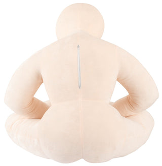 Beige plyschkudde i människoform med dragkedja på baksidan, avbildad sittande med benen i kors.